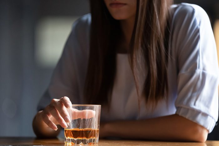 young woman sitting with alcoholic drink in front of her - alcohol