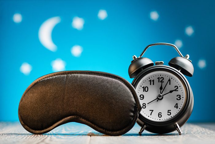 black sleeping mask next to old fashioned alarm clock - sleep