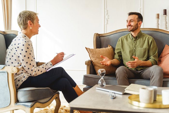 smiling man in therapy session with smiling female counselor - cognitive behavioral therapy
