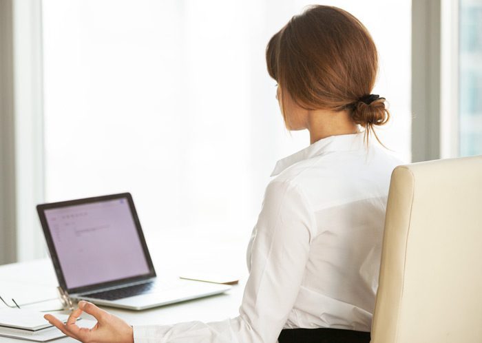 businesswoman practicing mindfulness meditation at her office desk