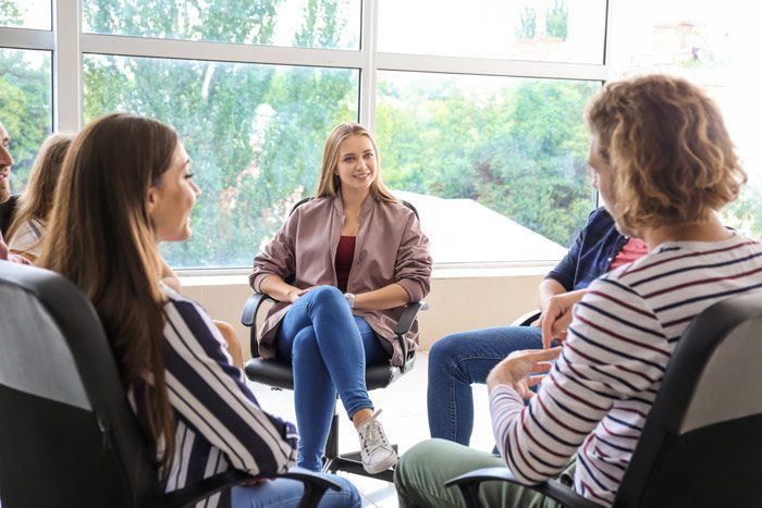 group of smiling people sitting in a circle for group therapy