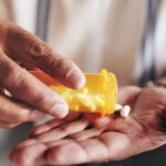 Close-up of hands pouring pills from an orange prescription bottle into an open palm.