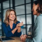 Peak View - Be Intentional When You Talk to Yourself and When You Talk About Others - Edited. Two women in an office setting have a friendly convorsation.
